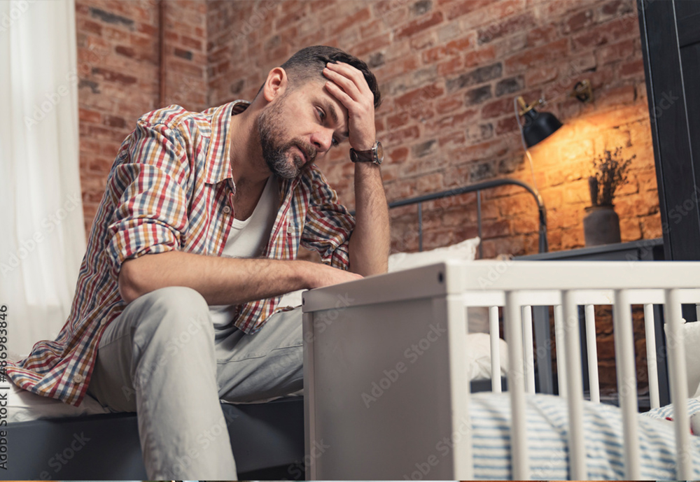 male-counselling-burlington-ontario male sitting, upset, and looking at a crib